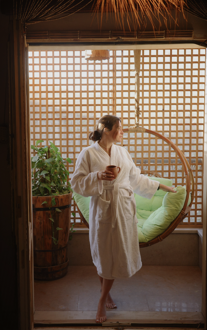 Guest in bathrobe enjoying morning coffee by hanging chair