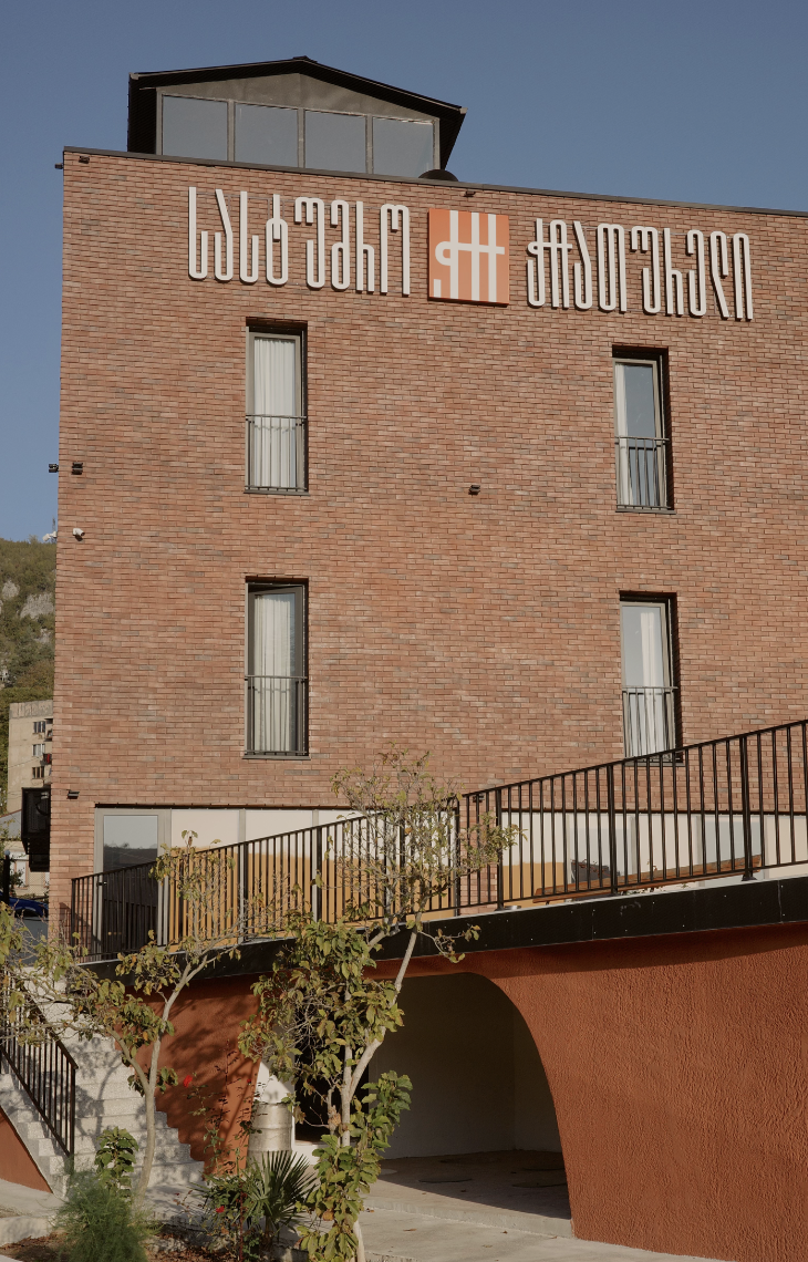 Chiatureli Hotel pool area with guest enjoying wine and view of the hotel building
