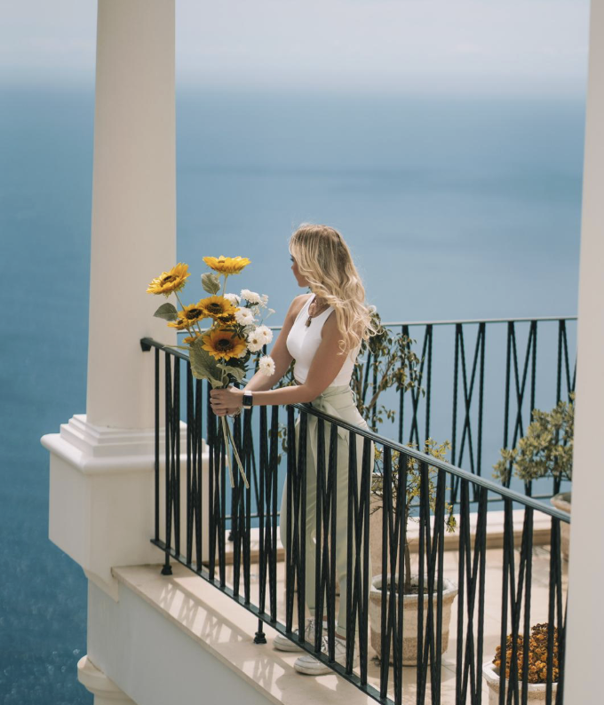 Woman with sunflowers on balcony overlooking the ocean
